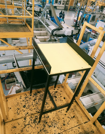 Mesa receptora elevada con rampa integrada instalada en mezzanine con barandales de seguridad
